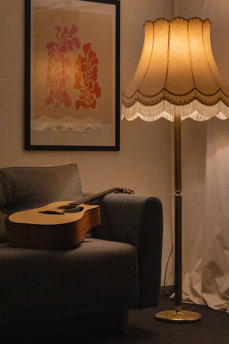 Akustikgitarre auf der Sofalehne neben der leuchtenden Fransen-Stehlampe.